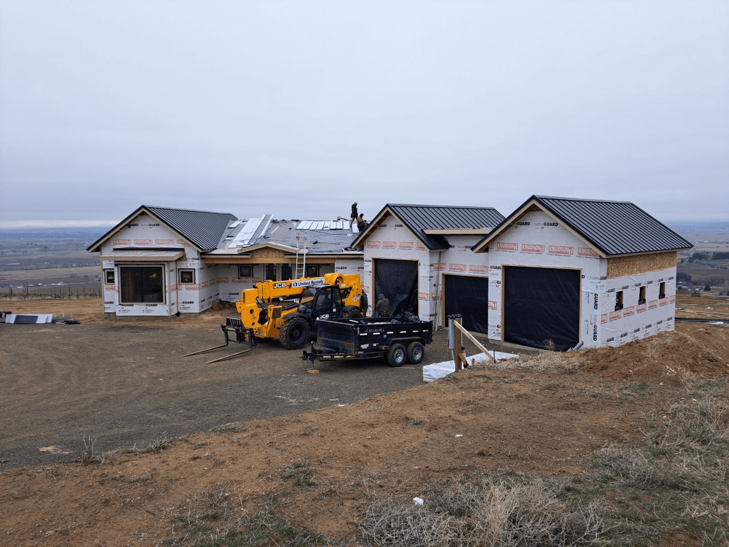 Roofing crew installing a metal roof on a home under construction